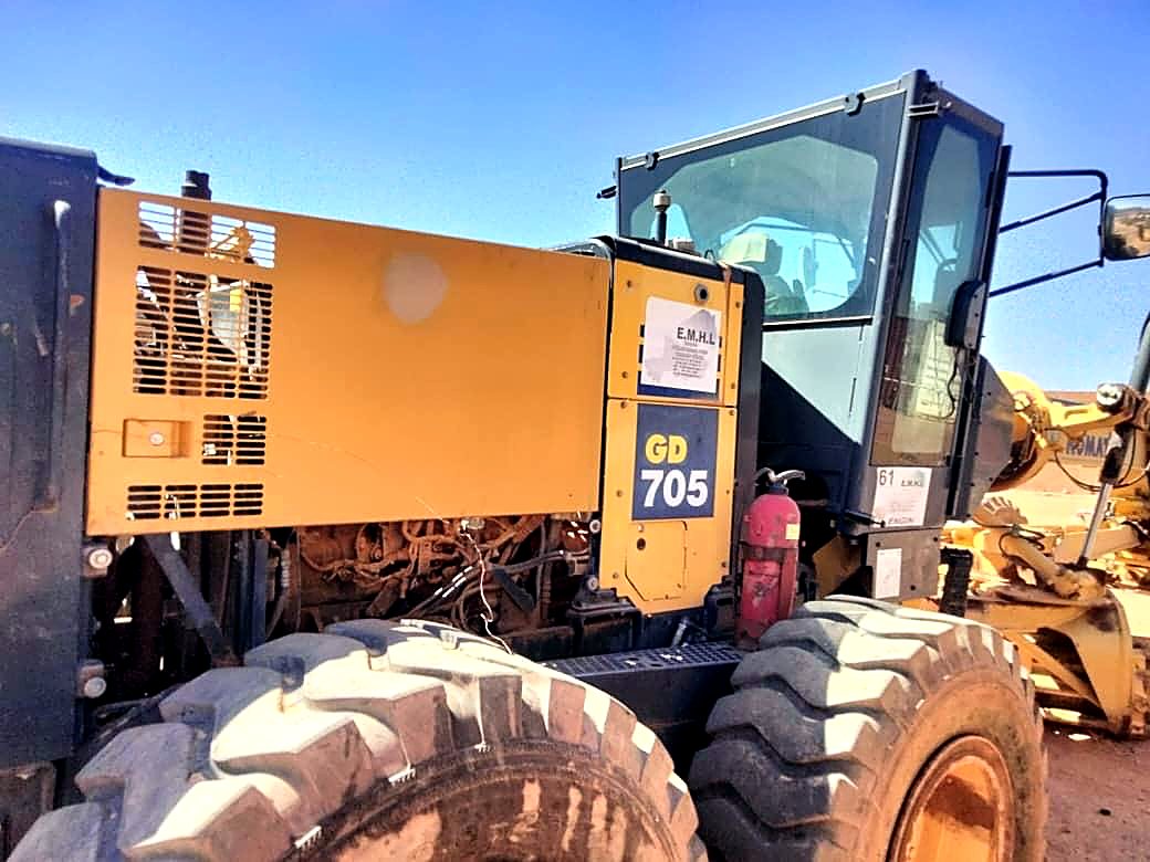 Niveleuse Komatsu GD705 stationnée dans le parc matériel EMHL